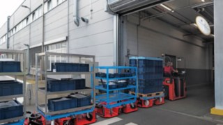 Ciągnik logistyczny LT10 WX firmy Linde MH transportuje materiał między dwiema halami