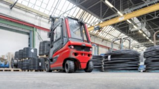 Kompleksowa koncepcja oddzielenia z elastomerowymi łożyskami, która tłumi wstrząsy na przedniej osi, zmniejsza fizyczne obciążenie operatora. Elektryczny wózek widłowy E30 firmy Linde Material Handling transportujący zwój przewodu
