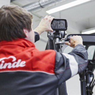 Mechanik Linde Material Handling montuje urządzenie Linde BlueSpot na dachu wózka widłowego.