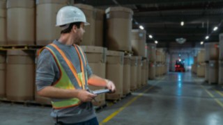 Interaktywna kamizelka ostrzegawcza Linde Material Handling zapewnia większe bezpieczeństwo Pracownik magazynu w interaktywnej kamizelce ostrzegawczej Linde Material Handling w słabo oświetlonym magazynie