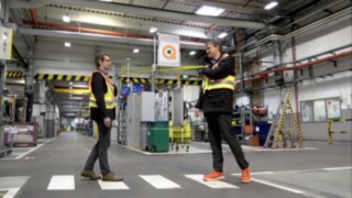 Dwóch pracowników fabryki wyposażonych w kamizelkę Linde Secure Distance Vest spotyka się w bezpiecznej odległości