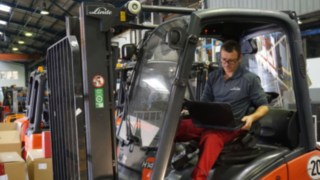 Pracownik techniczny przeprowadza przegląd używanego wózka widłowego Pracownik techniczny przeprowadza przegląd używanego wózka widłowego