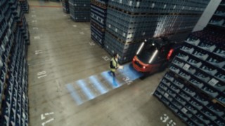 System wspomagania Linde Reverse Assist Radar podczas pracy. Pieszy przechodzi z tyłu wózka Linde X30.