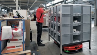 Pracownik firmy ABS Safety wyjmuje elementy z regału, który przetransportowała do niego platforma mobilna C-MATIC firmy Linde MH.