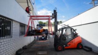 Wynajęty z firmy Linde wózek ostrożnie transportuje samochód wyścigowy na specjalnej platformie Wynajęty z firmy Linde wózek ostrożnie transportuje samochód wyścigowy