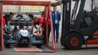 Wynajęty wózek widłowy Linde podnosi samochód wyścigowy na specjalnej platformie podczas studenckiej formuły na torze w Hockenheim Wynajęty wózek widłowy Linde podnosi samochód wyścigowy na specjalnej platformie