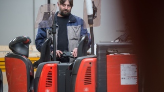 Pracownik Gusto AG ładuje wózek do komisjonowania z baterią litowo-jonową