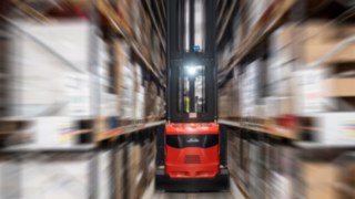 Wózek do wąskich korytarzy firmy Linde Material Handling podczas pracy w hali magazynowej.