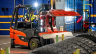Pracownik Michelin Tyre PLC chwyta stos opon za pomocą chwytaka do opon zamontowanego na Linde E20.