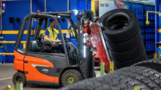 Pracownik Michelin Tyre PLC chwyta stos opon za pomocą chwytaka zamontowanego na wózku widłowym.