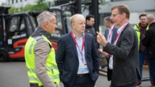 Do produkcji wodoru firma Linde wykorzystuje wyłącznie certyfikowaną ekologiczną energię elektryczną. Trzy osoby rozmawiają podczas otwarcia nowej instalacji do produkcji wodoru