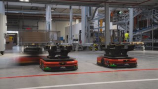 Trzy Autonomiczne Roboty Mobilne (AMR) firmy Linde MH poruszają się po magazynie