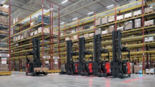 Pięć wózków R-MATIC firmy Linde Material Handling stoi w kolejce przed magazynem z szerokimi korytarzami firmy Simon Hegele.