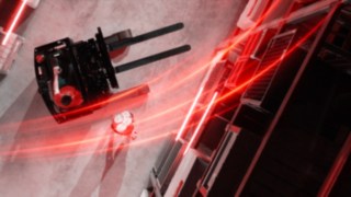 Widok z lotu ptaka na wózek wysokiego składowania Ri16 firmy Linde MH z czerwonymi liniami świetlnymi, a obok niego osoba stojąca na rękach.