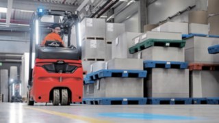 Do przodu czy do tyłu: ergonomiczna kabina minimalizuje obciążenie fizyczne operatora. Operator elektrycznego wózka widłowego Linde jedzie do tyłu przez magazyn.