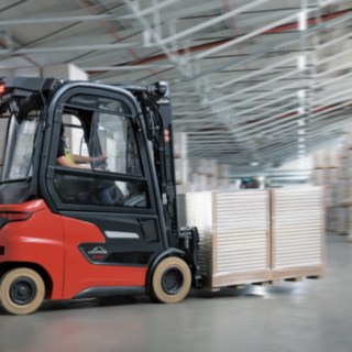 Modele E14 – E20 i Xi10 – Xi20 łączą wydajność, kompaktowość i elastyczność z rentownością, ergonomią i łącznością. Elektryczny wózek widłowy z przeciwwagą Xi20 podczas transportu towarów w magazynie.
