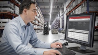 Szerokie możliwości w zakresie łączności zapewniają łatwą integrację wózków z systemami zarządzania flotą i procesami cyfrowymi. Osoba pracuje przy komputerze