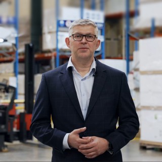 Grzegorz Bedna Dyrektor Techniczny TPV Displays stojący na tle magazynu z regałami systemowymi