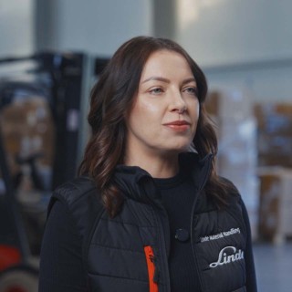 Joanna Kossakowska, Starszy Specjalista ds. Wynajmu Linde Material Handling Polska, stojąca w magazynie cargo na tle wózka widłowego