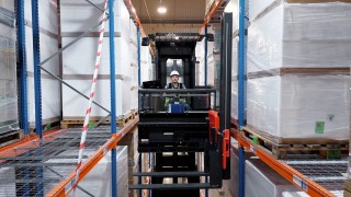 Operator wózka widłowego VNA w magazynie pomiędzy regałami systemowymi