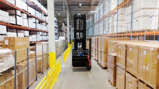 Operator w wózku widłowym systemowym VNA Linde w alejce magazynowej pomiędzy regałami